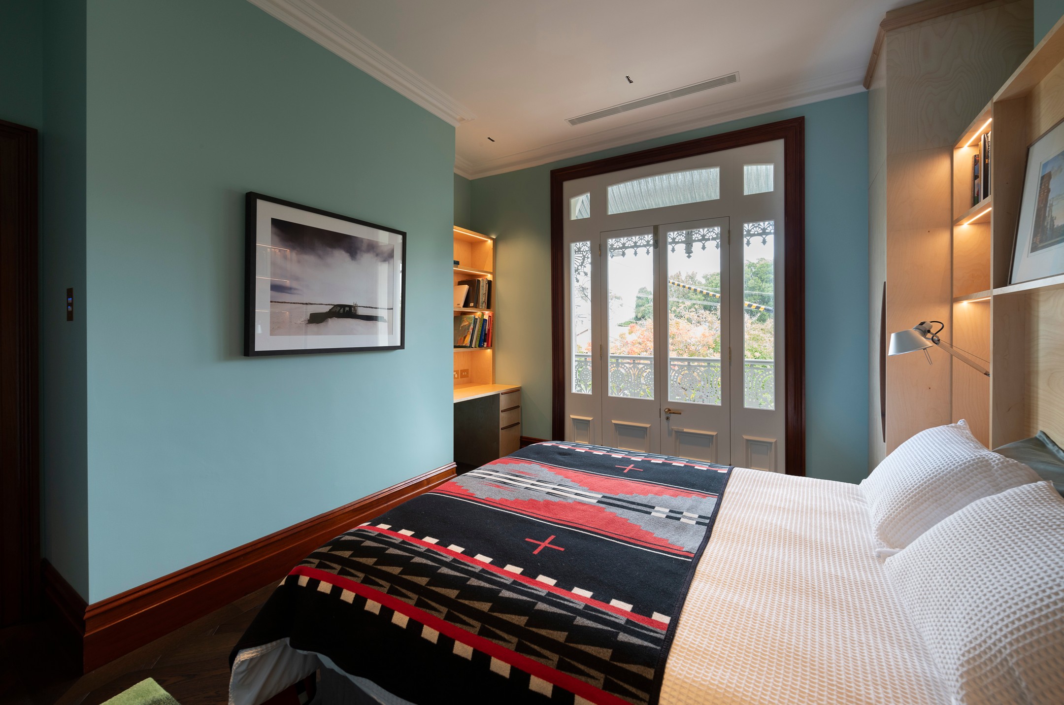 Heritage bedroom with timber-framed French doors, built-in shelving and a lacework balustrade view